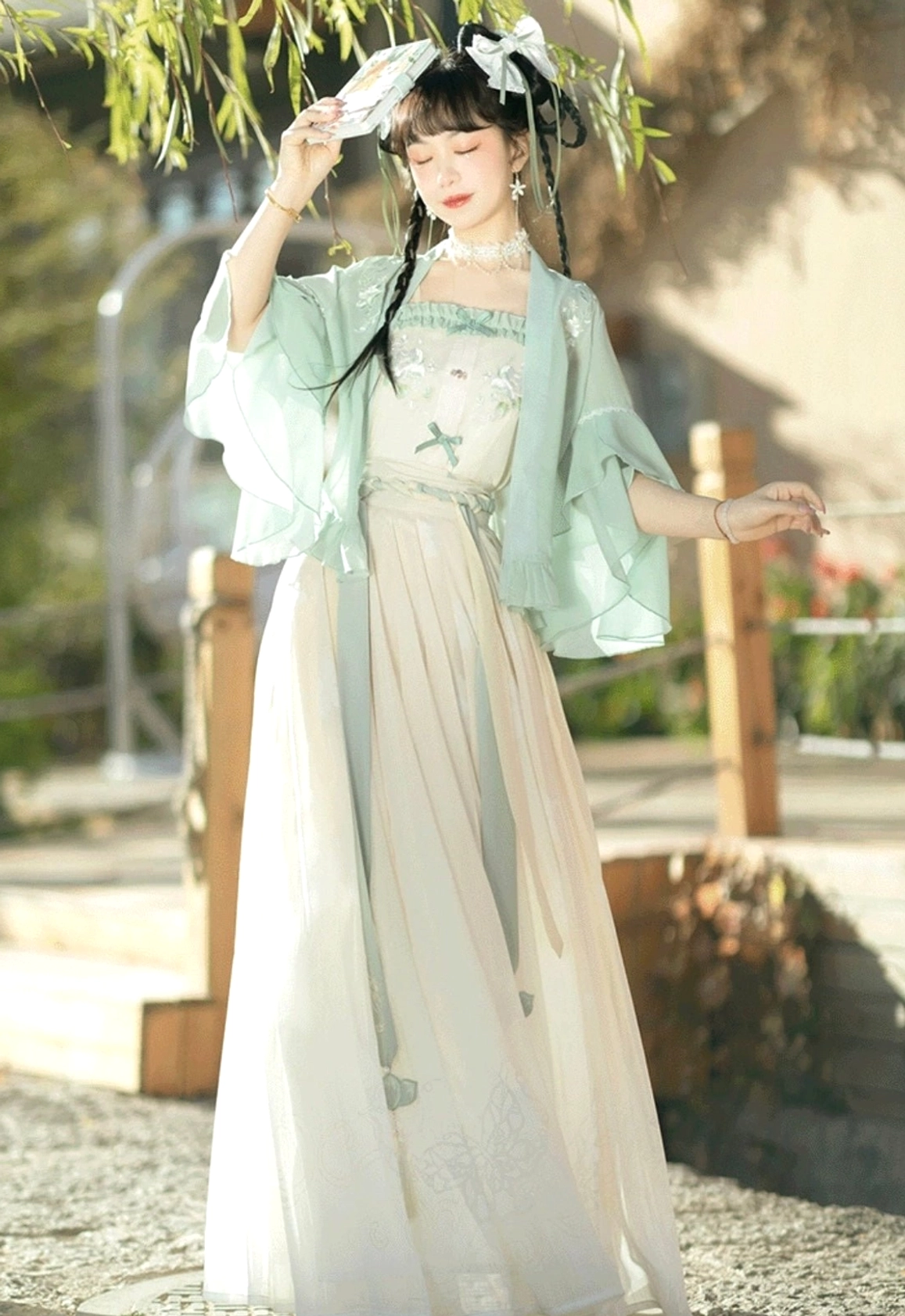 Mint green modern Song style Hanfu three-piece set with embroidered cardigan off-white camisole and flowing pleated skirt shown in an ancient Chinese town