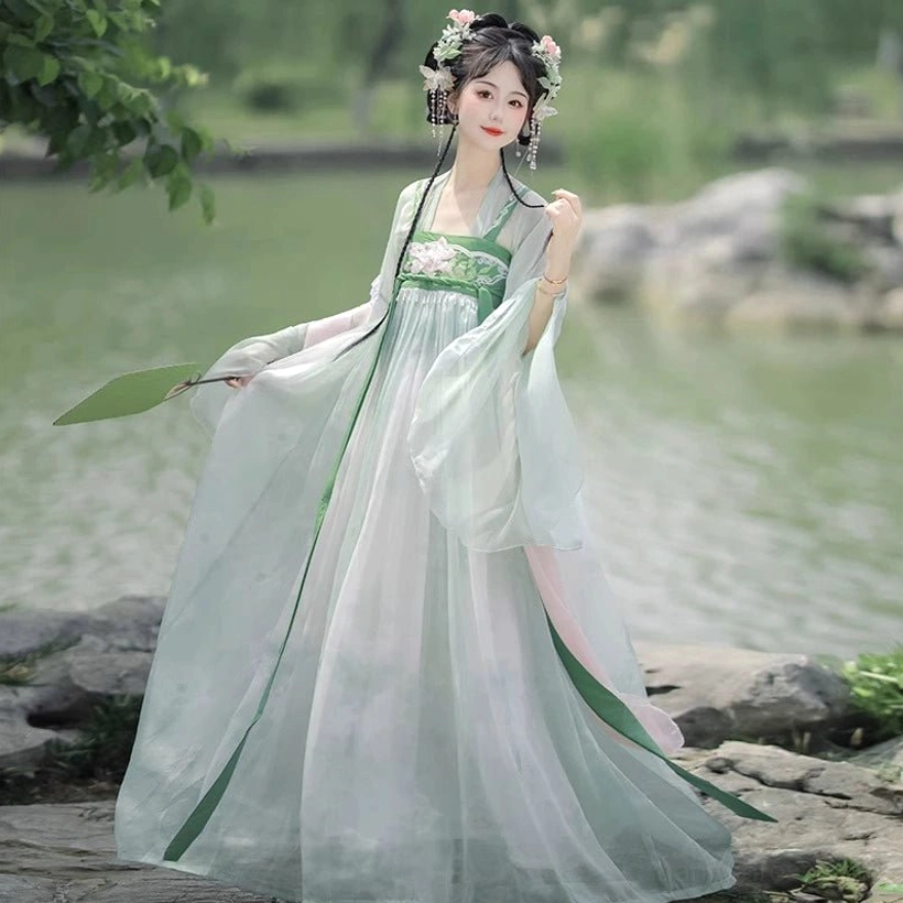 Rear three-quarter view of mint green Tang Dynasty Qixiong Ruqun Hanfu complete set showing long green back sashes, flowing wide sleeves, and garden setting