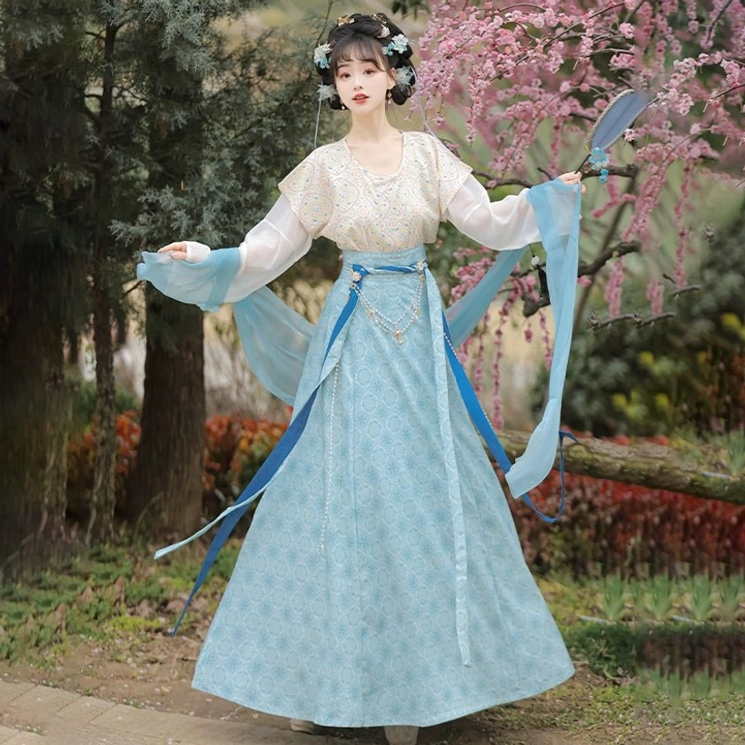Blue round collar qiyao ruqun Hanfu outfit with coordinated waist sash and blue fan in a traditional garden setting
