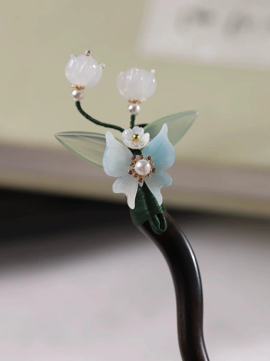 Close-up of handmade Chinese floral hair stick with white bell flowers blue orchid pearl detail and wooden shaft