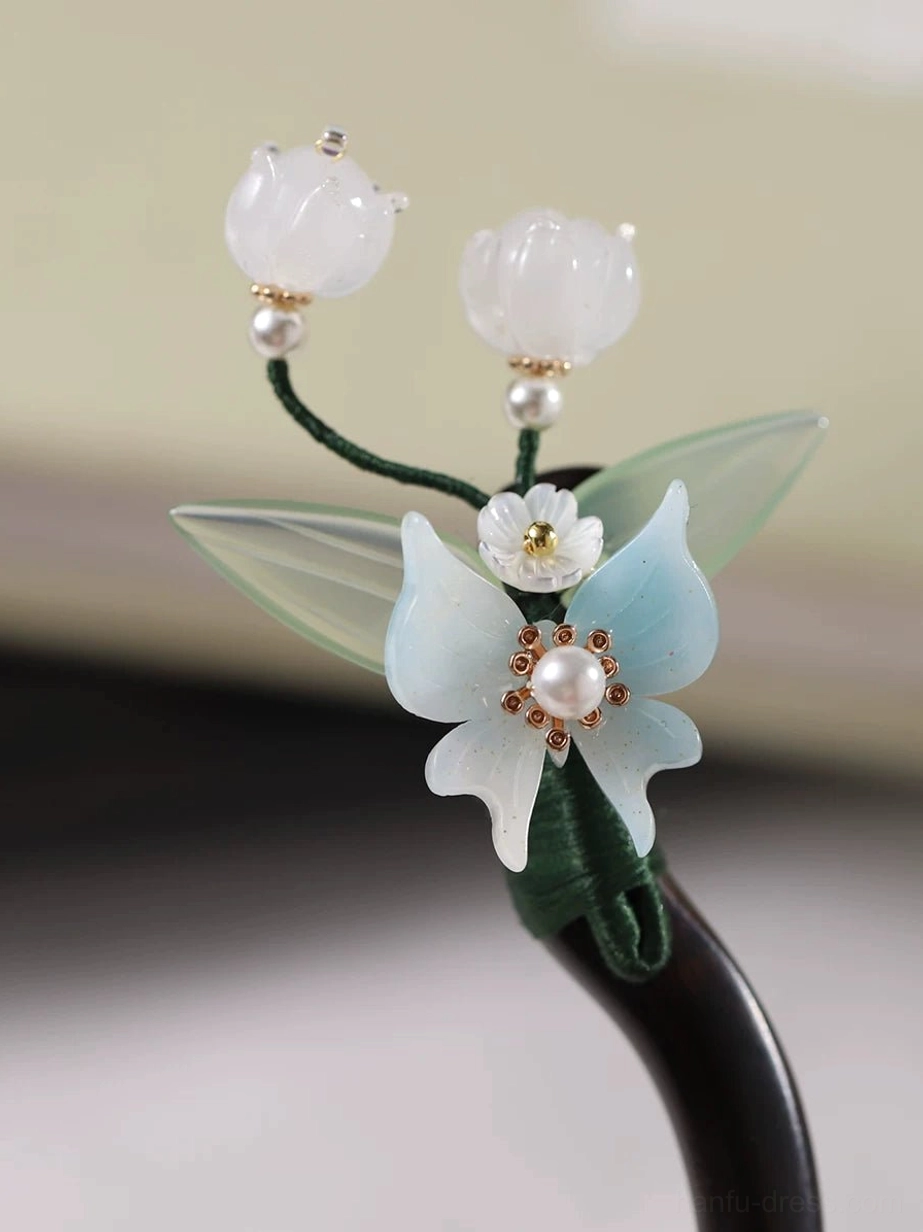 Side view of lily of the valley orchid Hanfu hair stick with green leaves and curved dark brown wooden pin