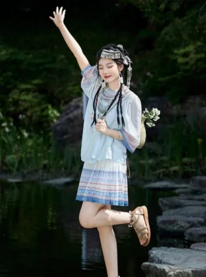 Misty Morning modern Hanfu two-piece outfit with sky-blue round-neck top and pleated ethnic-style skirt worn beside a traditional Chinese waterside garden