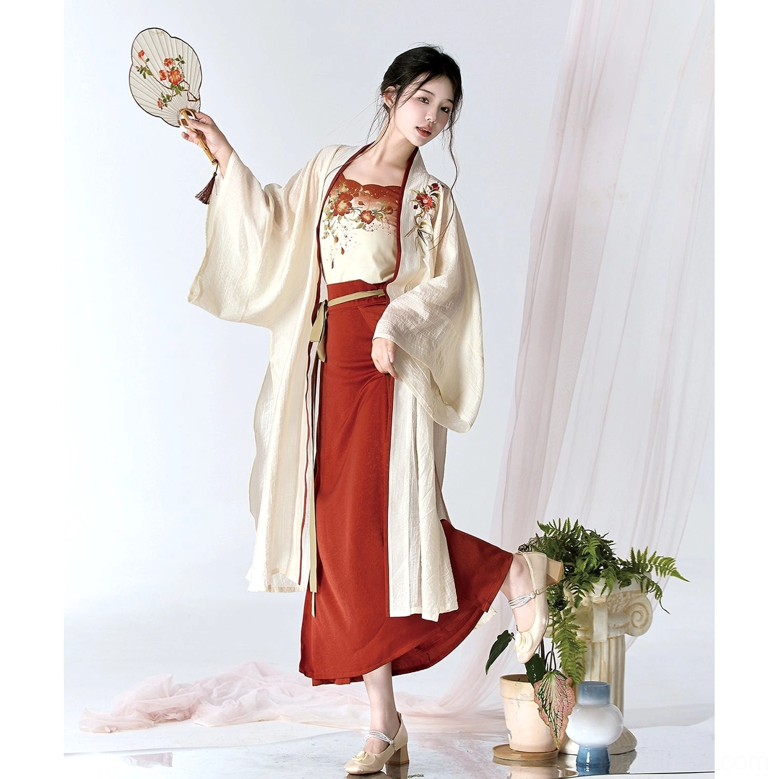Three-quarter view of modern camellia Song Dynasty Hanfu showing the open cream cardigan, floral camisole, and burgundy skirt slit