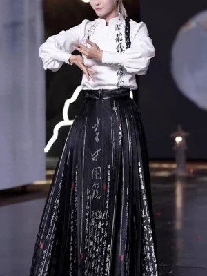 Front detail of a contemporary Chinese Hanfu outfit showing the stand collar white blouse, expressive calligraphy patterns, structured pleated horse-face skirt, and monochrome Ming-inspired fashion design