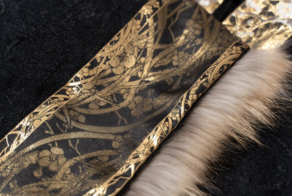 Close up of intricate gold vine and floral decorative trim on black modern Chinese Hanfu coat with light brown fur edge detailing
