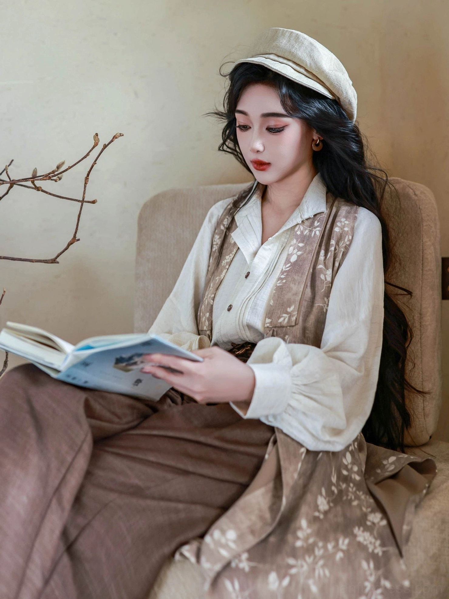Model seated in a vintage interior wearing a modern Chinese hanfu outfit with puff sleeve top, botanical floral robe, and tailored high-waisted wide leg trousers