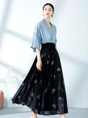 Front three quarter view of modern Chinese Hanfu outfit featuring a light blue satin cross collar blouse and black sheer gold embroidered mamian skirt