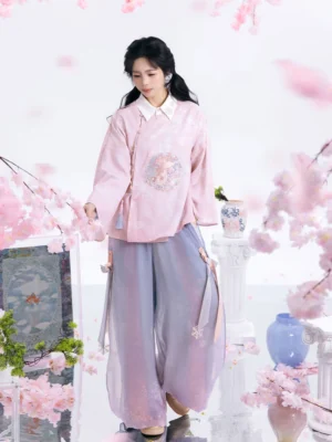 Modern Chinese Hanfu cross collar outfit with pink floral top and purple wide leg trousers in a relaxed side view