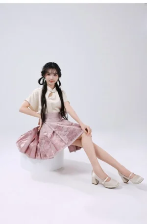 Modern Chinese Hanfu outfit with pink pleated mamianqun horse face skirt and beige stand-collar top in a seated studio pose