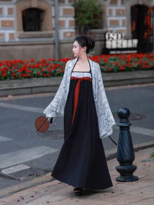 Back three-quarter view of a modern Chinese Hanfu set with black Qixiong dress, red sash, and white botanical print jacket worn outdoors