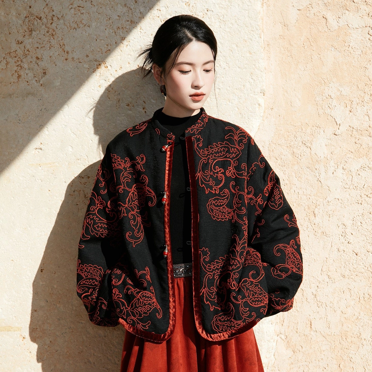 Close-up front view of a modern Chinese stand collar jacket with red cord embroidery, velvet trim, and decorative beaded buttons