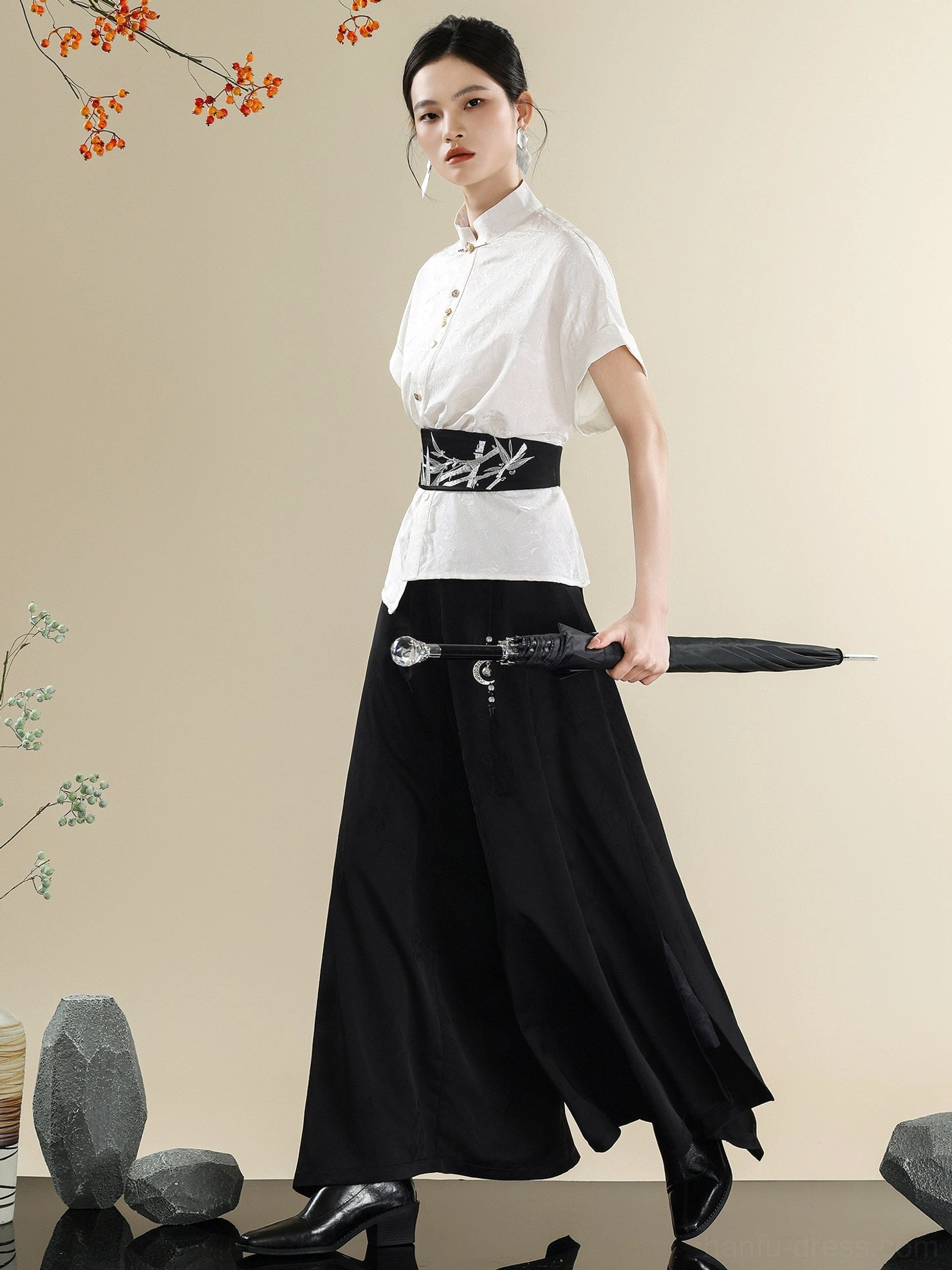 Three-quarter view of a modern Chinese clothing set with white stand collar shirt, black embroidered waist belt, wide-leg trousers, and black umbrella