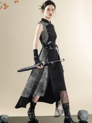 Three-quarter view of a Chinese-inspired sleeveless qipao style dress with ink-wash color blocking, asymmetric layered lace hem, embroidered waist accessory, and modern black boots