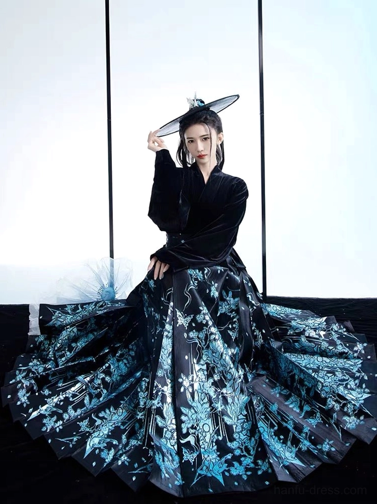 Modern Chinese mamianqun Hanfu outfit displayed in a seated three-quarter view with the wide pleated skirt spread to reveal the complete blue floral pattern