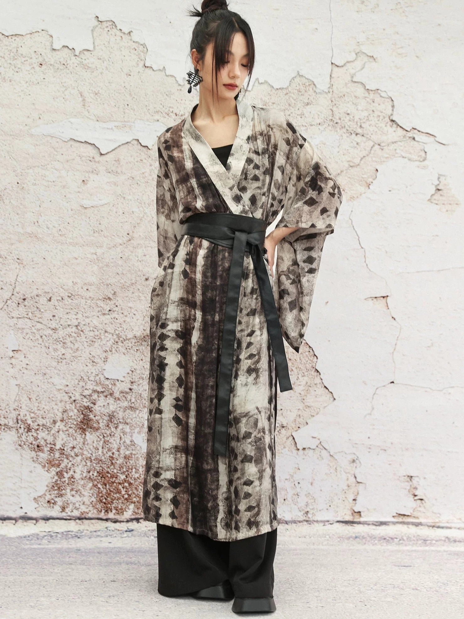 Front view of modern Chinese style Hanfu cardigan with brown grey geometric tie dye print, black wide waist belt, and black wide leg trousers