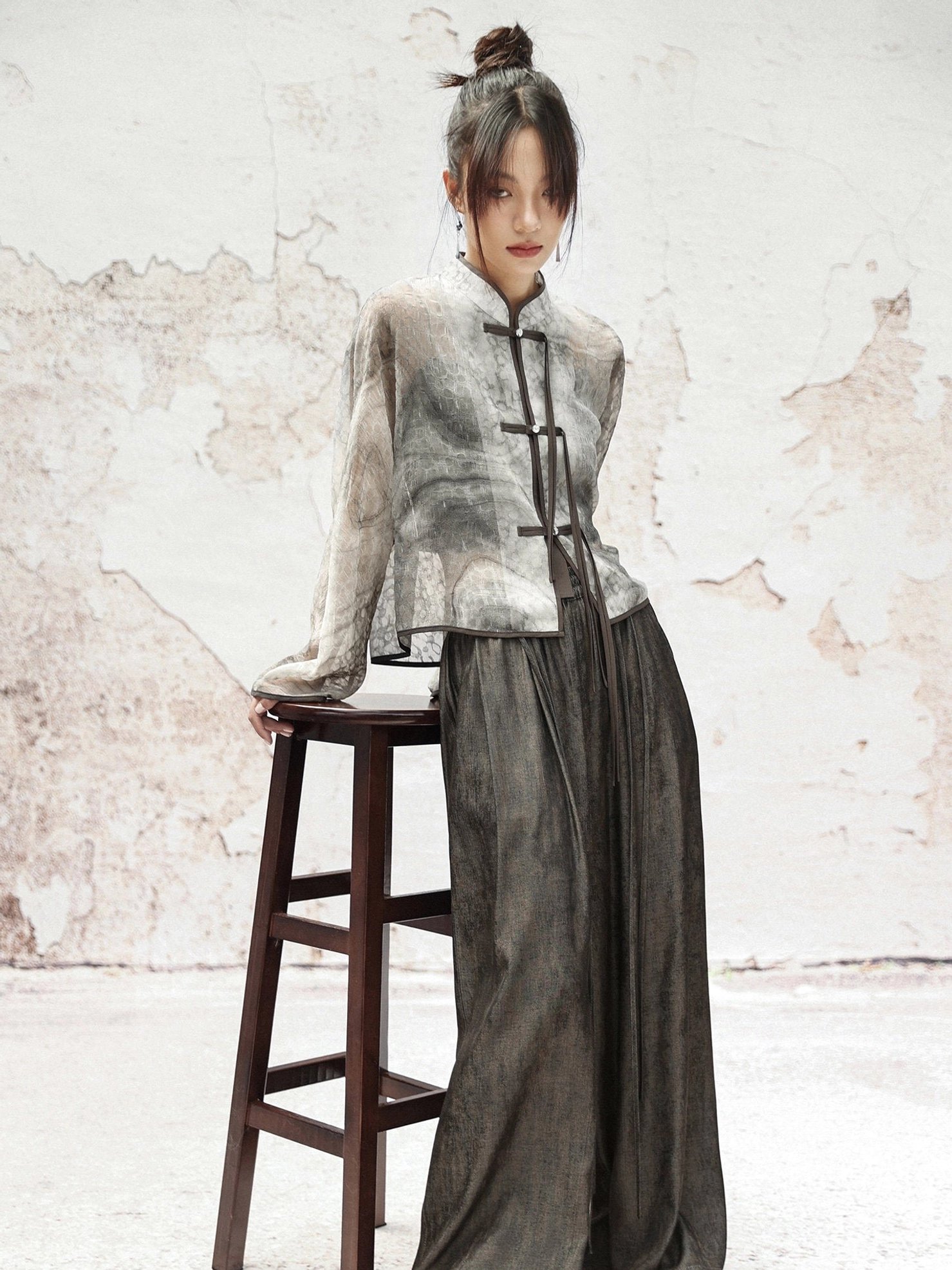 Back three-quarter view of a contemporary Chinese-style Hanfu jacket with sheer graphite ink print, cropped hem, and traditional frog fasteners