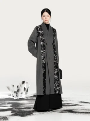 Three-quarter view of a Chinese-style ash grey Hanfu overcoat showing the double-breasted closure, shawl lapel, side pocket, and relaxed fit with wide-leg trousers