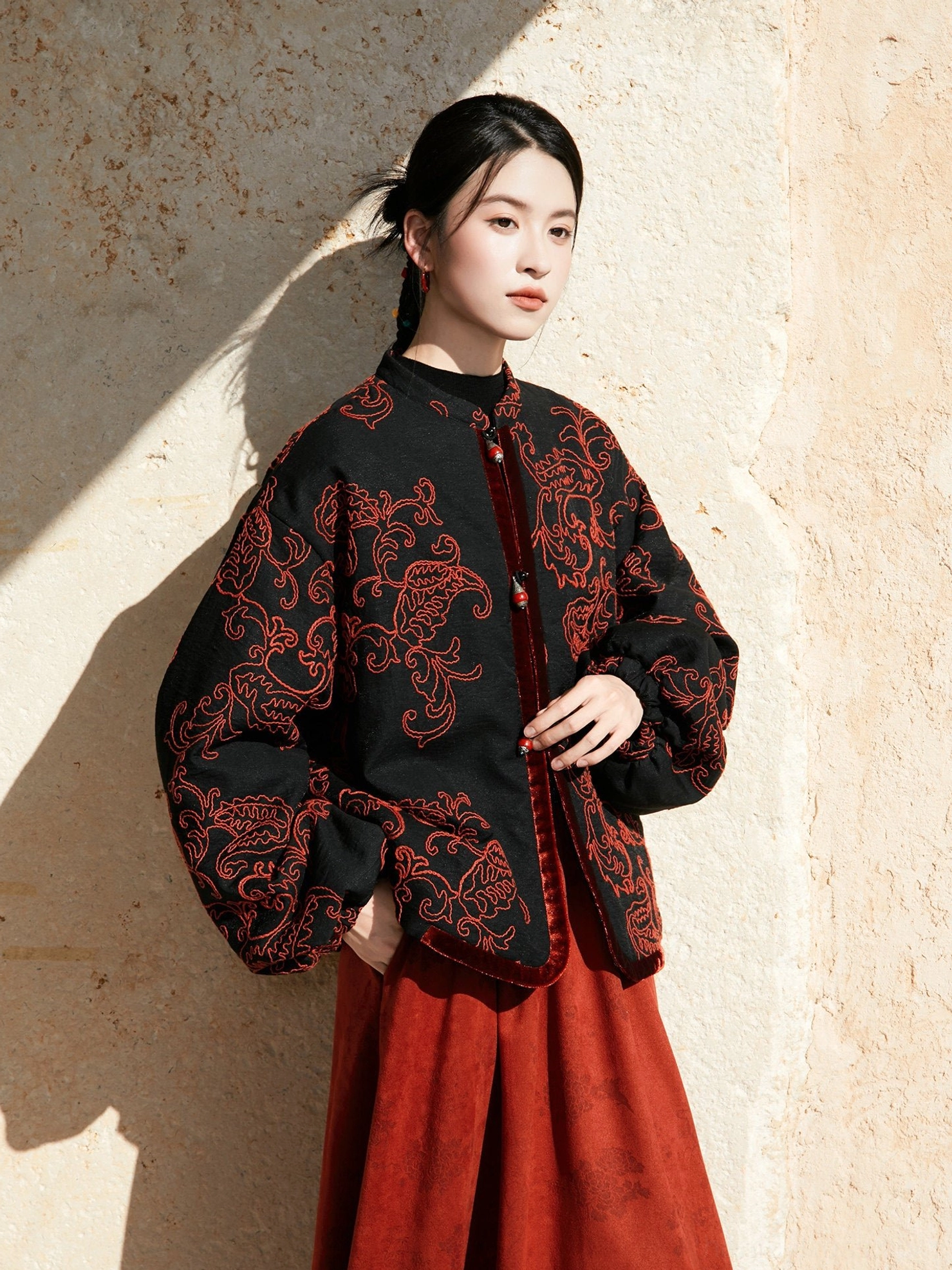 Front three-quarter view of a modern Chinese style Hanfu jacket with red paisley embroidery, velvet placket trim, and beaded buttons