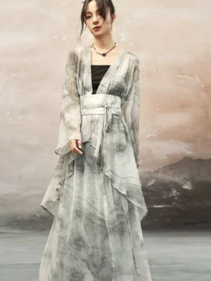 Three-quarter view of a Chinese-style ink-print long cardigan with lightweight draped fabric, waist sash styling, and irregular layered hem