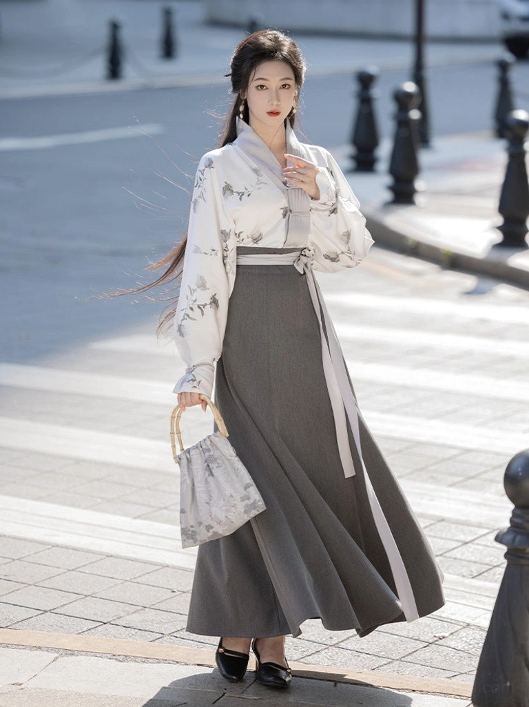Front three quarter view of modern everyday Hanfu clothing with grey floral cross collar top charcoal wrap skirt and handbag