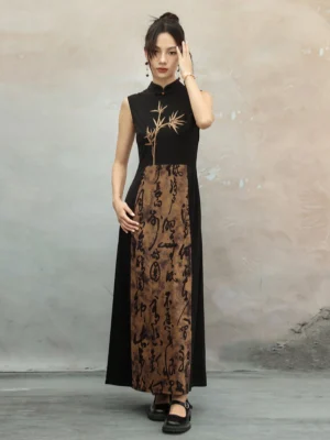 Three-quarter front view of a sleeveless modern Hanfu cheongsam dress with golden bamboo print, Chinese calligraphy panel, black and brown color blocking, stand collar, and floor-length silhouette