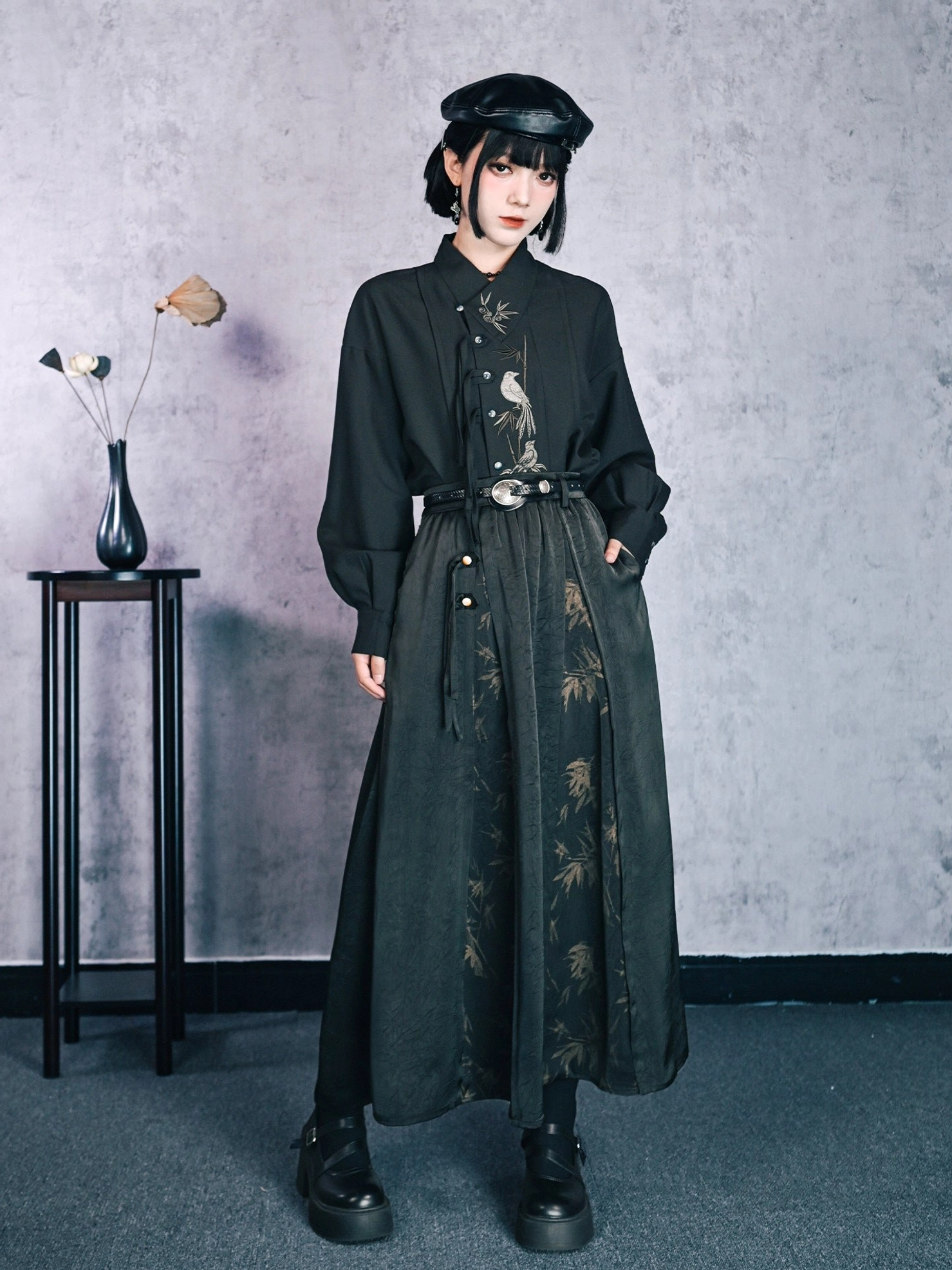 Full front view of a modern Hanfu bamboo print high-waisted maxi skirt styled with a dark embroidered blouse, leather belt, lantern sleeves, and black beret