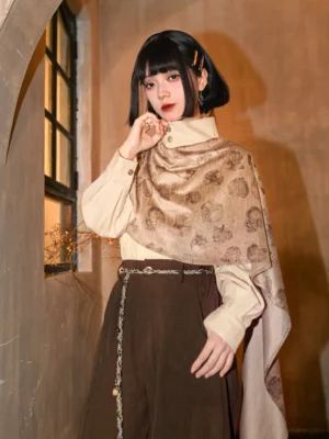 Three quarter front view of a woman wearing a beige modern Hanfu long sleeve top with detachable asymmetric vintage printed cape, dark brown skirt, and tassel waist chain in a retro studio