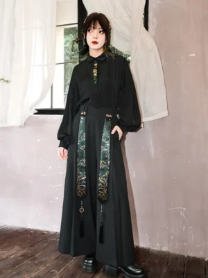 Modern Hanfu black wide-leg pants styled with a matching stand-collar blouse, featuring green and gold snake-pattern tassel waist details