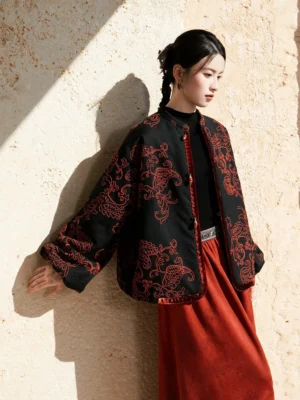 Modern Hanfu black jacket with red paisley cord embroidery, stand collar, lantern sleeves, and warm red skirt styling in an outdoor portrait