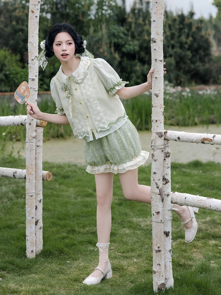 Front three-quarter view of a light green modern Hanfu blouse and elastic waist bloomers with floral collar embroidery and front button closure
