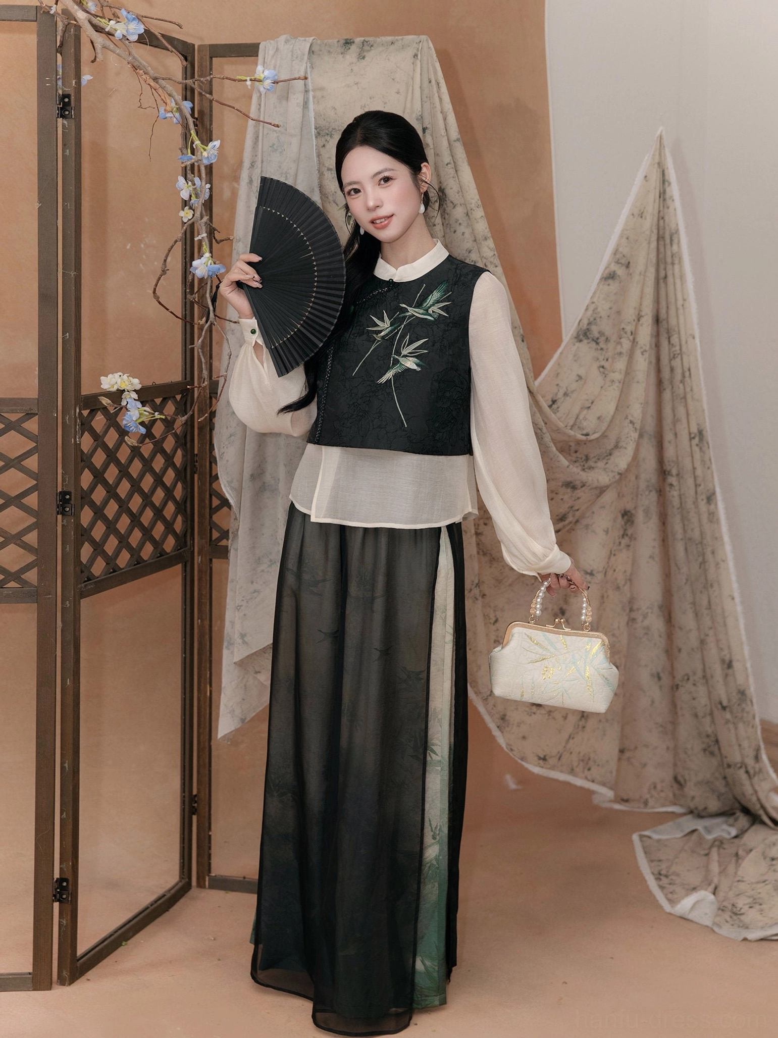 Front full view of a modern Hanfu blouse and ink-wash wide leg pants set with bamboo embroidery, Chinese knot buttons, folding fan, and traditional interior styling