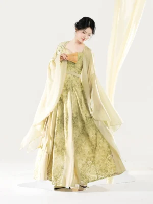 Front three-quarter view of a women’s modern Hanfu Camellia Water dress set in matcha green with a pleated slip dress, floral embroidery, and flowing wide-sleeve chiffon cape