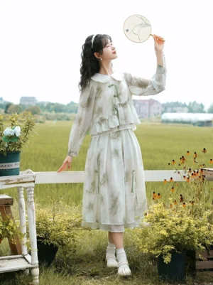 Side view of modern Chinese Hanfu-inspired two-piece dress featuring sheer long sleeves, layered midi skirt, ink-wash plant print, and green tassel decorations