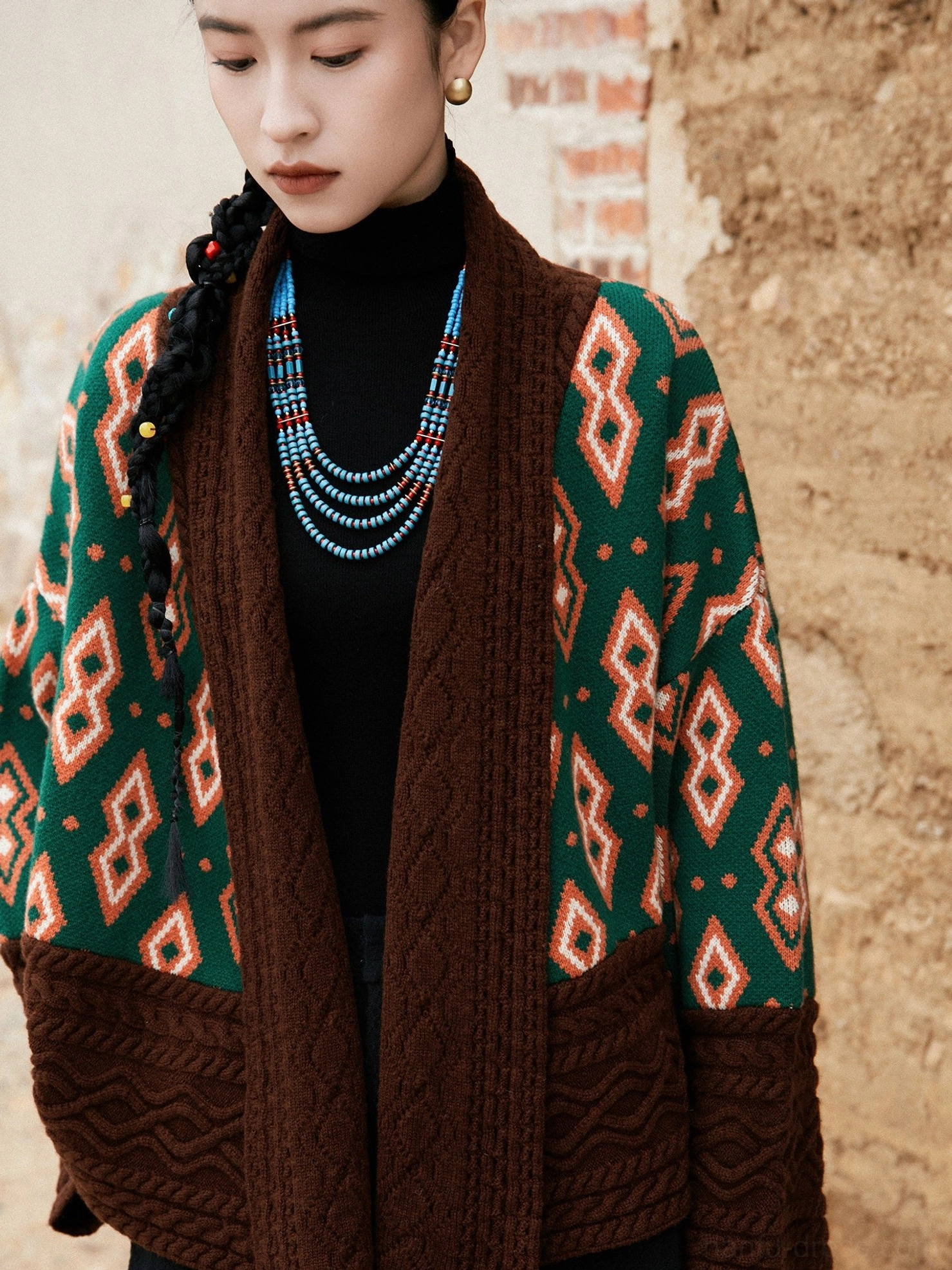 Close-up detail of modern Hanfu contrast color knitted jacket showing cable knit texture green wool fabric orange diamond motifs and brown trim