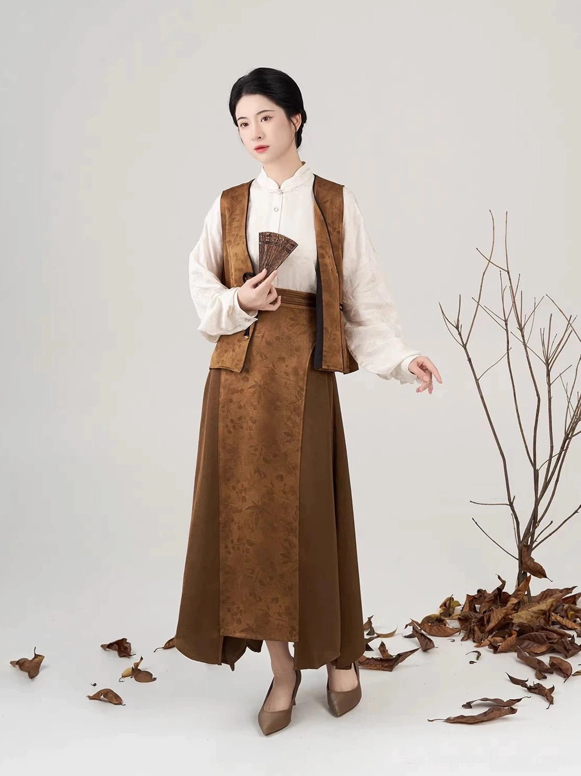 Side front view of Modern Hanfu set with cream puff pipa sleeves brown vest long skirt and folding fan