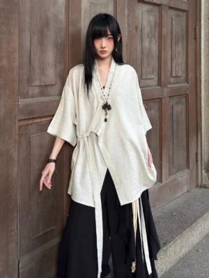 Front full-body view of a beige modern Hanfu cross-collar half-sleeve cardigan with textured fabric, oversized fit, and asymmetrical side tie closure