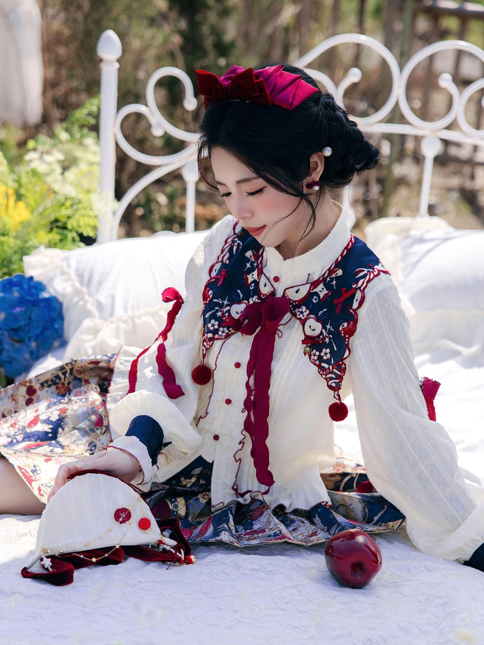 Close view of detachable embroidered cloud collar with red velvet bow and pompom pendants from modern Hanfu set