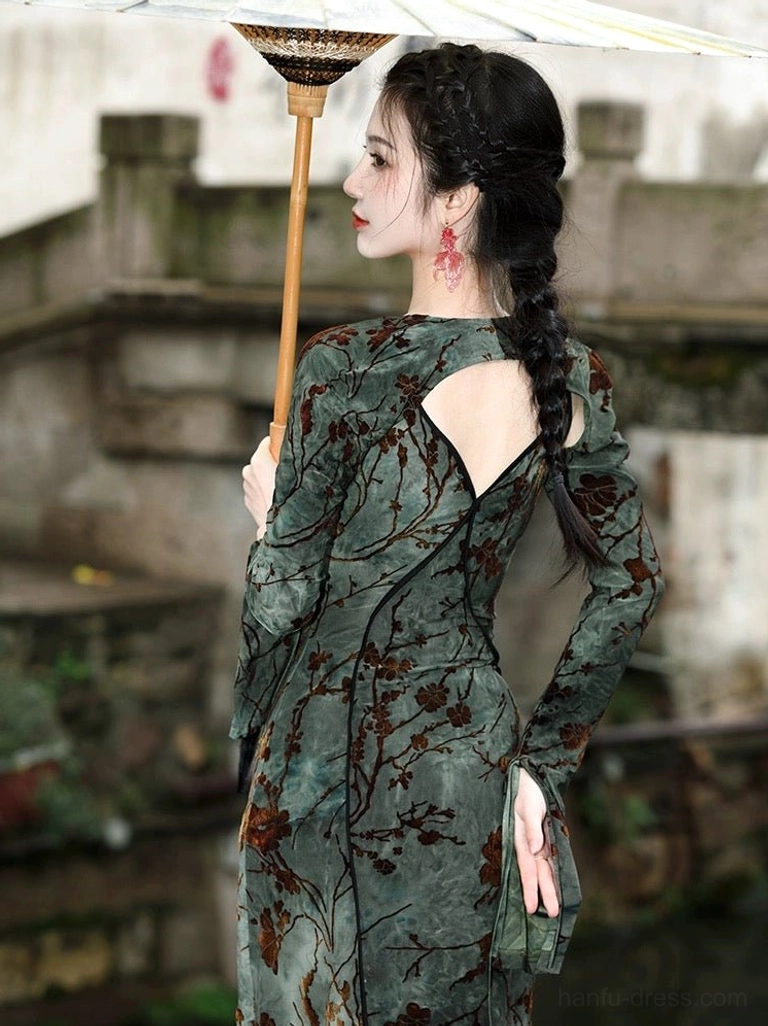 Rear three-quarter view of modern green floral Hanfu dress showing back cutout, black trim, detachable flared long sleeves, and elegant silhouette on a traditional stone bridge