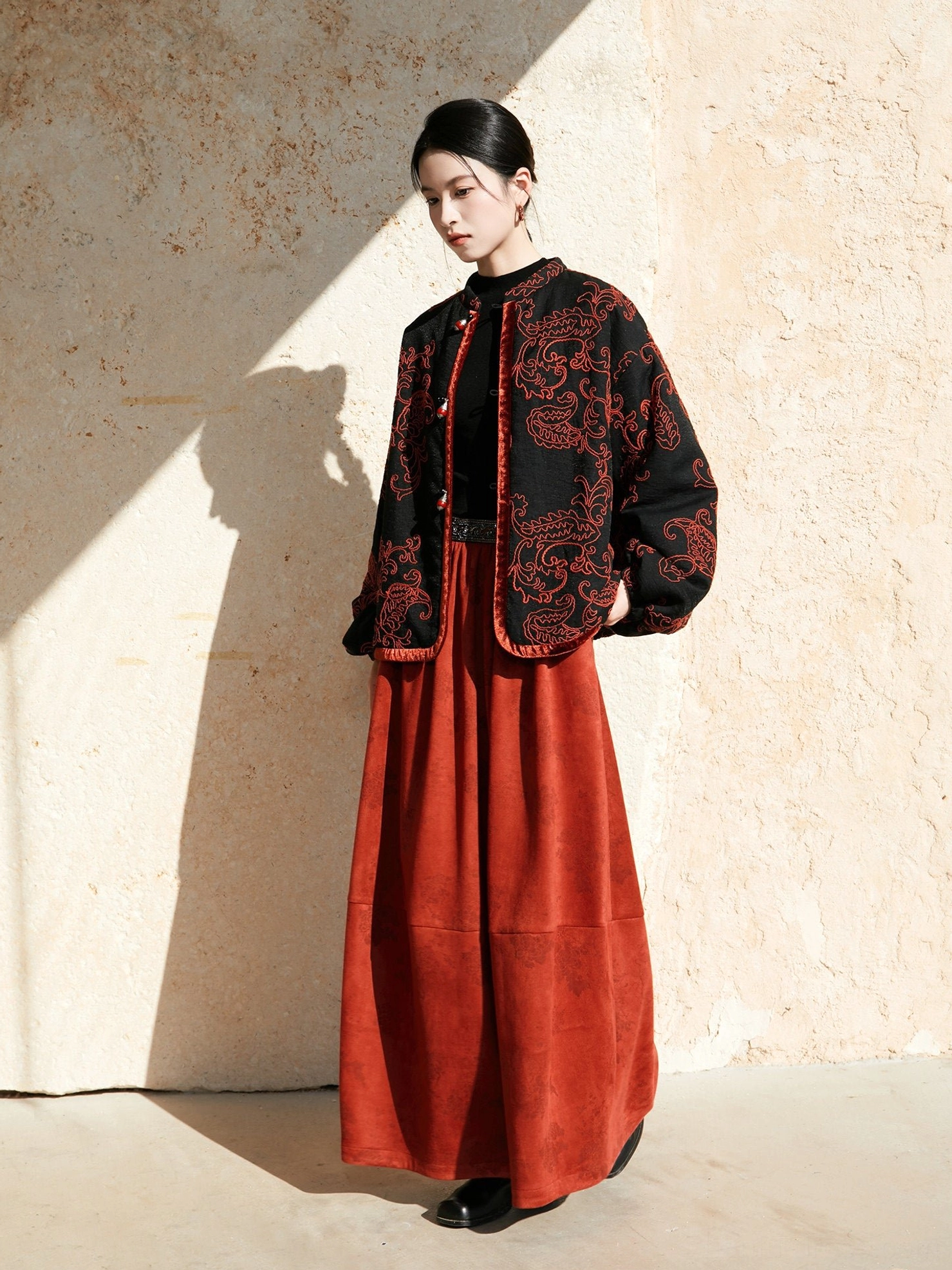 Full-body modern Hanfu outfit featuring a loose black embroidered jacket with red paisley patterns and a floor-length red skirt