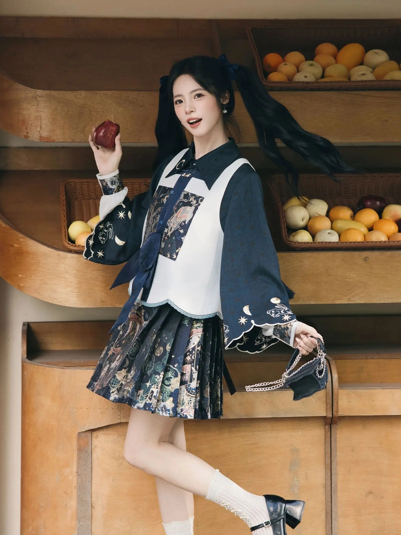 Three-quarter front view of a modern Chinese Hanfu fashion look with contrasting vest, embroidered cuffs, neck sash, and pleated printed skirt styling