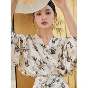 Modern Hanfu ink bamboo satin wrap dress front close-up showing V-neckline relaxed batwing sleeves glossy fabric and black Chinese ink bamboo print
