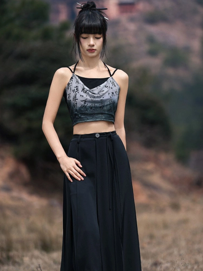 Modern Hanfu ink calligraphy cropped camisole styled with high waisted black wide leg trousers in an outdoor mountain landscape