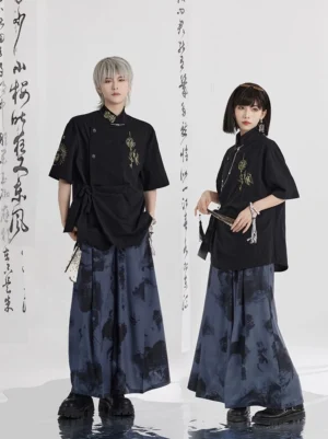 Two models wearing modern Hanfu outfits with a black stand collar shirt and dark navy ink wash floral print wide leg pants in a minimalist Chinese calligraphy studio