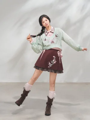 Side view of a modern Hanfu inspired three piece outfit with mint cropped knit top, burgundy embroidered mini skirt, and layered Chinese style blouse