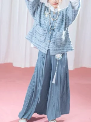 Modern Hanfu jacket and wide-leg pants outfit showing the round stand collar, front patch pockets, decorative tassel pendant, and relaxed pleated silhouette