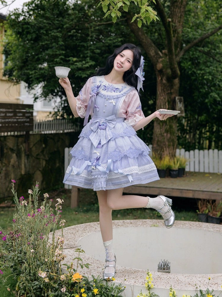 Front full body view of a lavender purple modern Hanfu inspired summer dress and pastel pink blouse outfit with lace trims bows and layered ruffles in a garden setting
