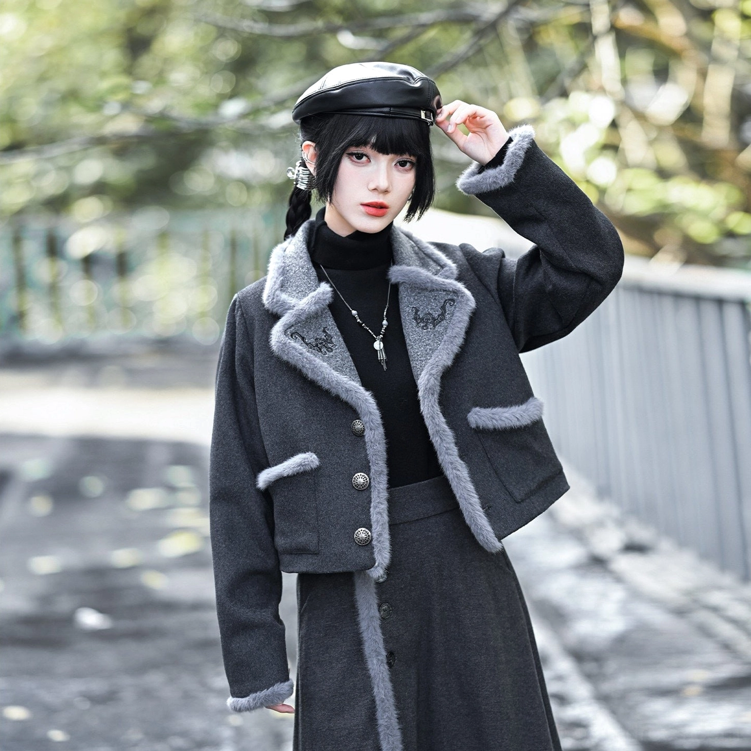 Close-up of modern Hanfu charcoal wool blend jacket showing detailed lucky bat embroidery on the collar, silver front buttons and textured cuff trim