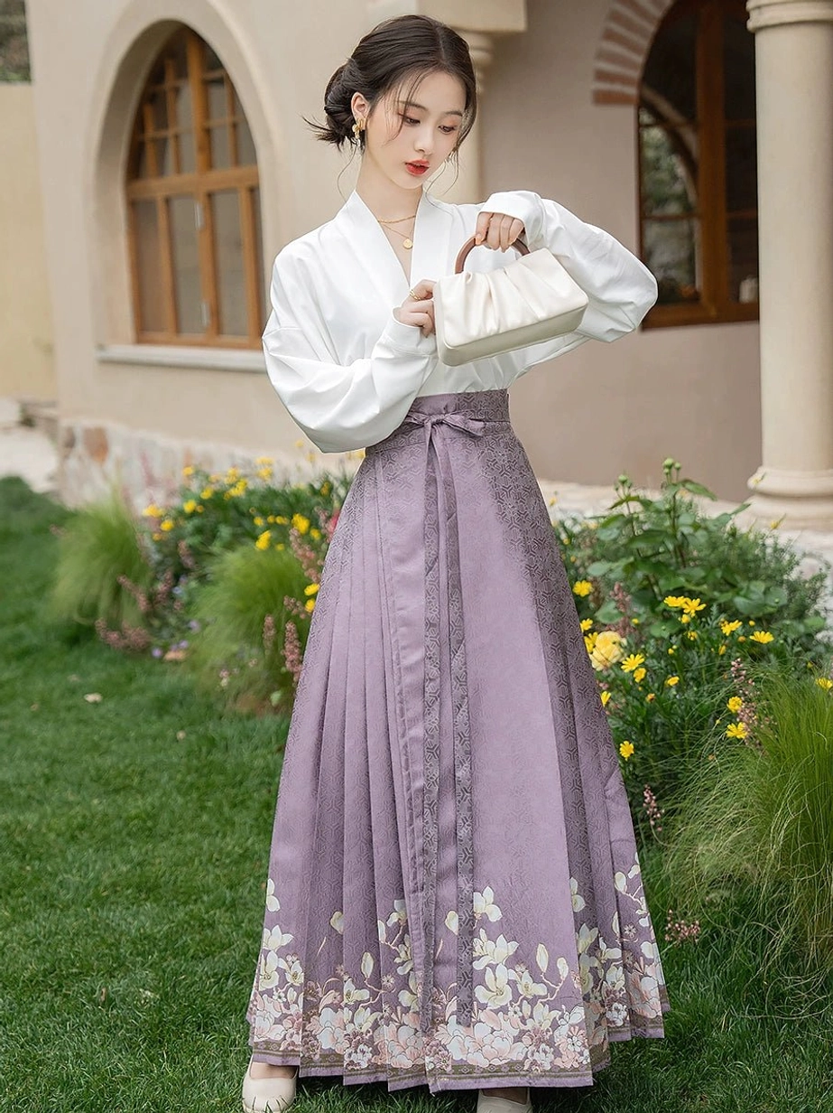 Front view of a modern Hanfu mamianqun outfit with long lantern sleeves, a white cross-collar blouse, pleated dusty purple horse face skirt, jacquard texture, and floral hem decoration