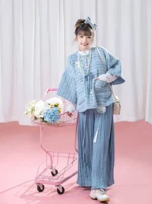 Full-body view of a modern Hanfu Ming-inspired matching set in mist blue and white with a textured cardigan, pleated wide-leg pants, and layered pearl necklaces