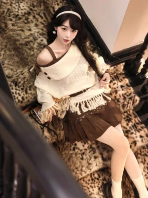 Modern Hanfu off-shoulder knitted cloak and pleated skirt set in cream and brown with tassel fringe styling on a vintage staircase